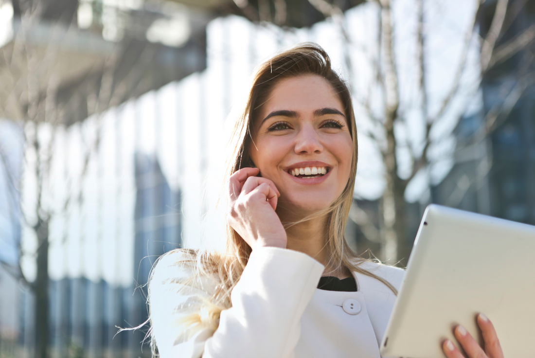 Woman on the phone smiling because she has registered for the GRE.