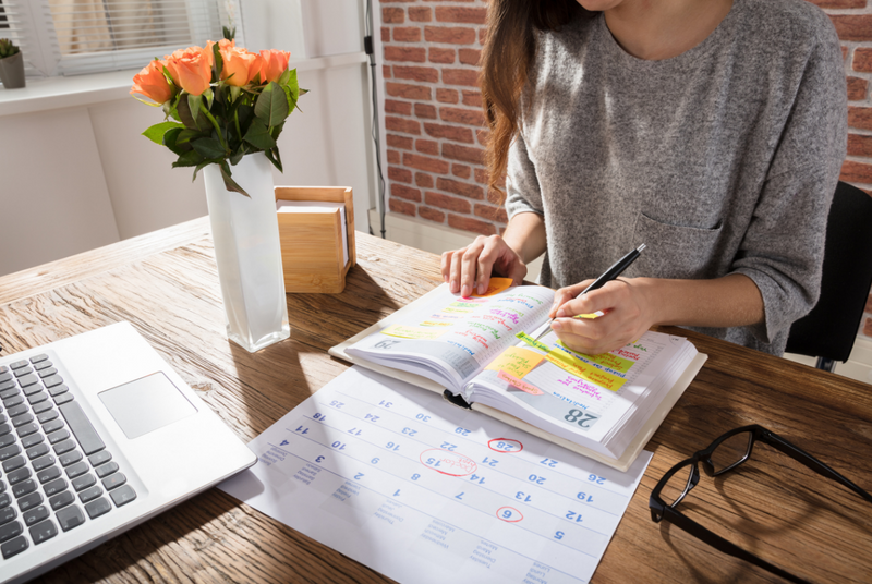 A woman creates her GMAT study schedule and writes it in her planner.