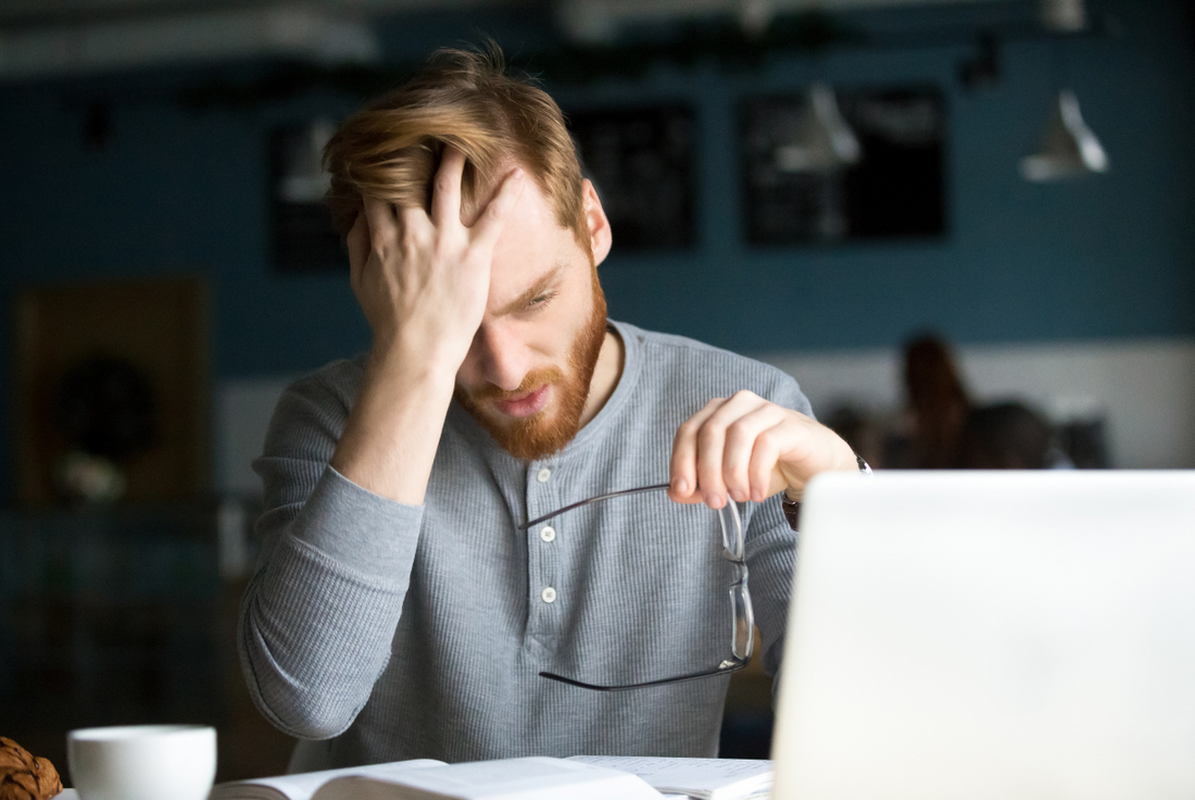 Man looking at a laptop with his hand on his forehead feeling stressed about the MCAT's difficulty.